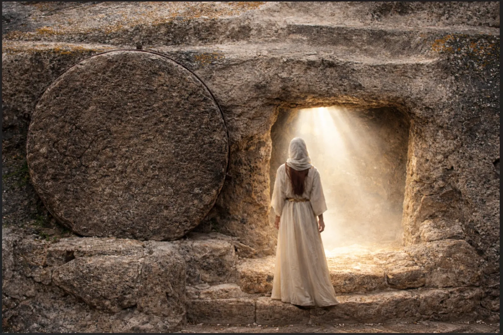 A woman facing the light inside the empty tomb